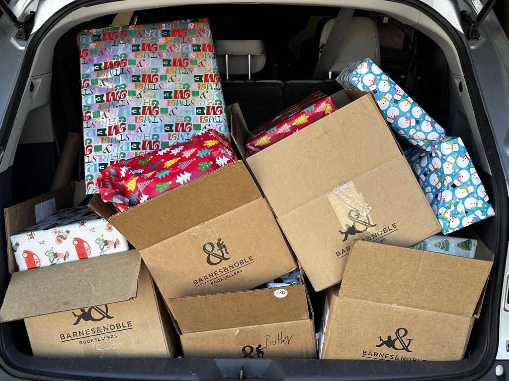 Wrapped presents and labeled boxes packed into a car trunk